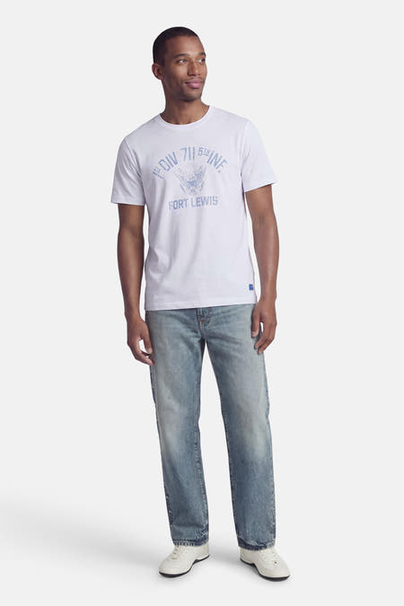 Wit T-shirt van PREMIUM BLUE by JACK & JONES, met blauwe tekstprint op de voorkant, gecombineerd met blauwe jeans en witte sneakers.