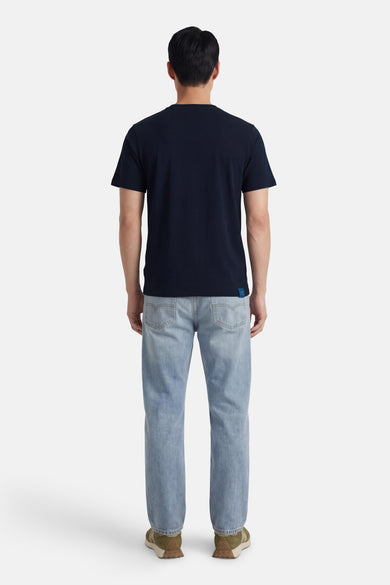 Blauw T-shirt van PREMIUM BLUE by JACK & JONES, met korte mouwen, gedragen met lichte jeans en groene sneakers, gezien van achteren.
