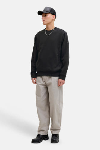 Pull noir de CORE BY JACK & JONES, à manches longues et col rond, associé à une chaîne argentée et une casquette.