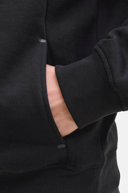 Sweat-shirt noir de CORE BY JACK & JONES, avec une main dans la poche et un poignet côtelé à la manche.