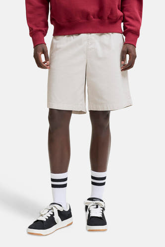 Beige short van JACK & JONES JEANS INTELLIGENCE, gedragen met een rood sweatshirt, gestreepte sokken en zwarte sneakers.