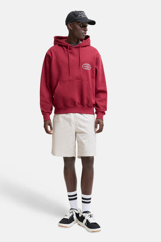 Beige short van JACK & JONES JEANS INTELLIGENCE, gedragen door een model met een rode hoodie en sneakers.