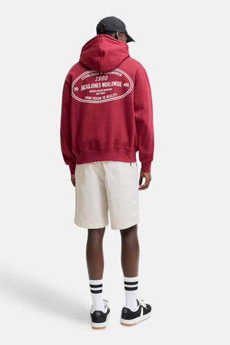 Beige short van JACK & JONES JEANS INTELLIGENCE met een achterzak, gedragen door een man met een hoodie en sneakers, van achteren gezien.