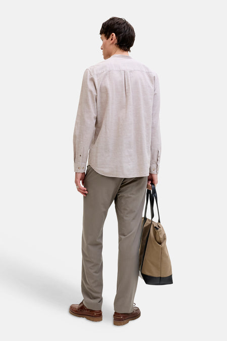 Grijze chino van PREMIUM by JACK & JONES, gecombineerd met bruine boots en een canvas tas met leren details, gezien van achteren.
