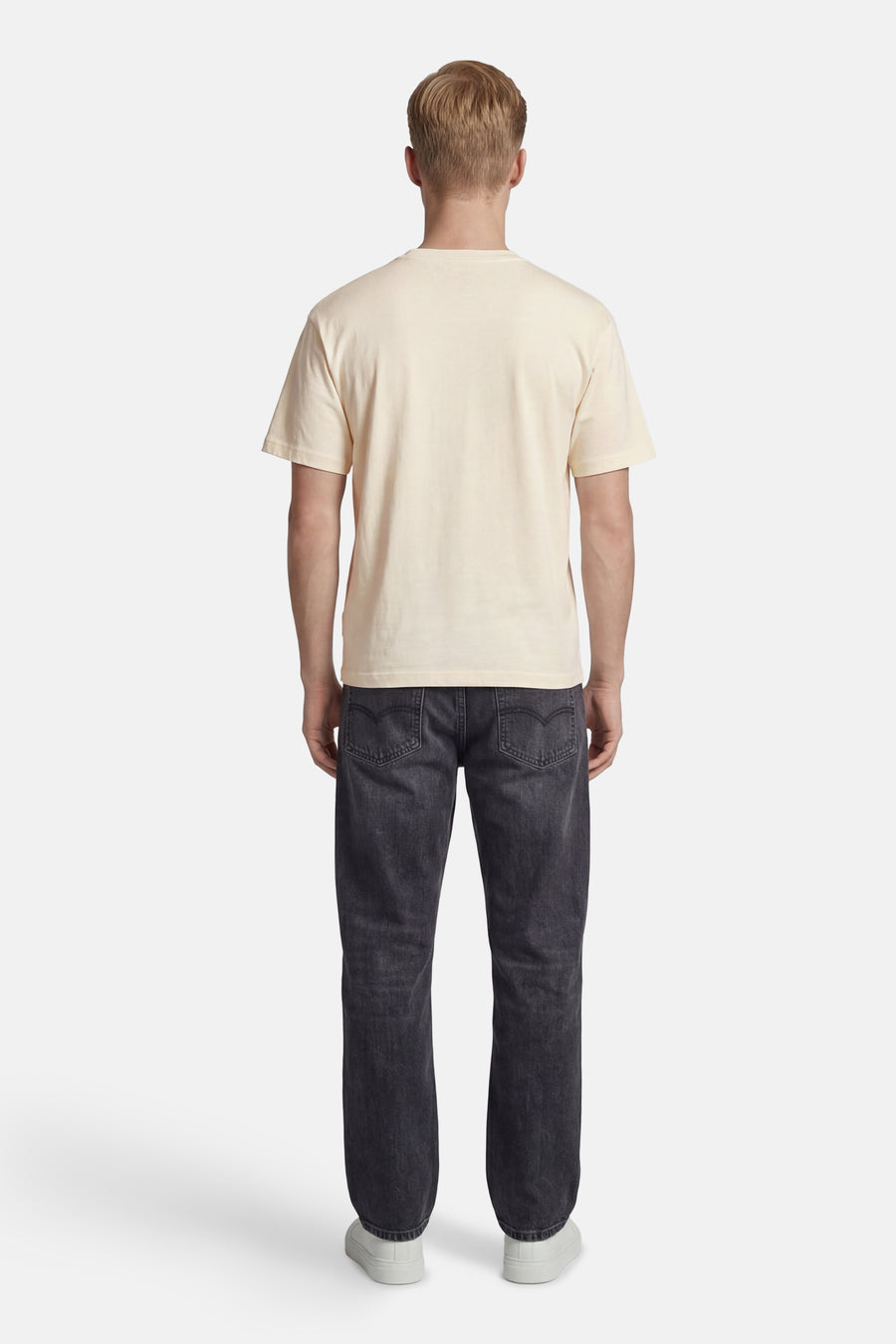 Ecru T-shirt van ORIGINALS BY JACK & JONES met ronde hals, gedragen door een man in donkere jeans en witte sneakers, rugaanzicht.