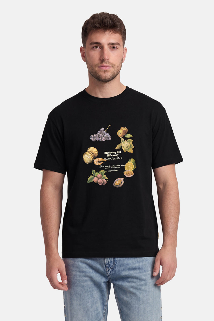 Zwart T-shirt van ORIGINALS BY JACK & JONES met kleurrijke print van vruchten en schelpen, gedragen door een man in jeans.