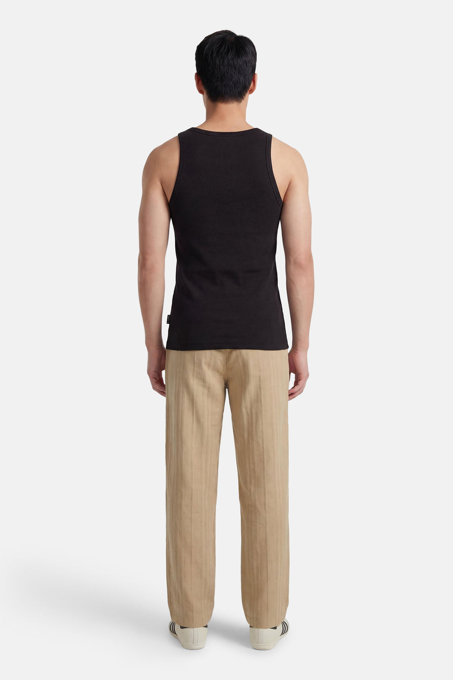 Zwart singlet van CORE BY JACK & JONES, met ribtextuur, gecombineerd met beige gestreepte pantalon en witte sneakers.
