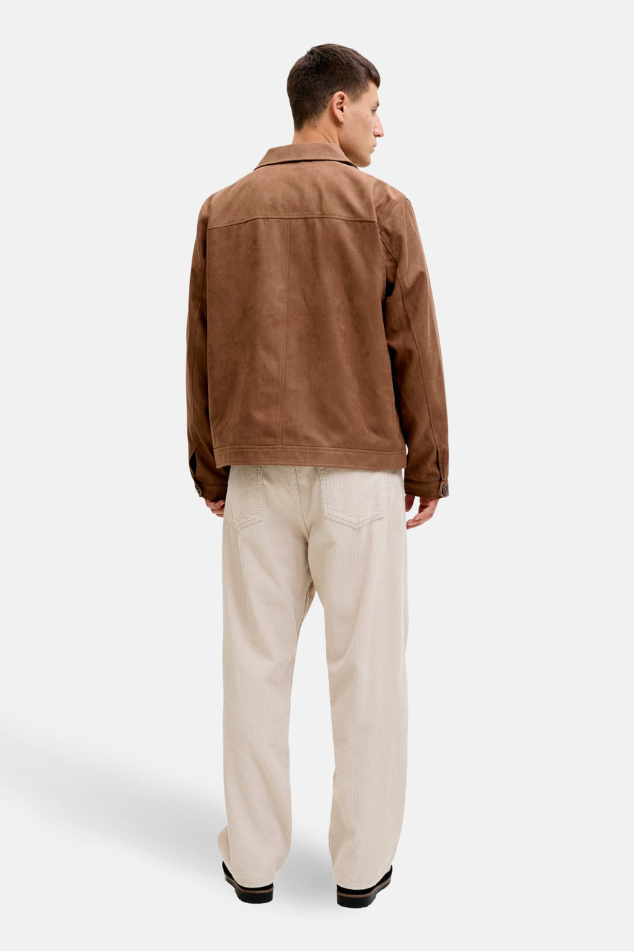 Man van achteren, bruine jas, beige corduroy broek.
