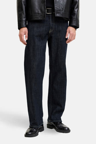 Jeans straight van donkerblauw denim door JACK & JONES JEANS INTELLIGENCE, met gele stiksels en zwarte leren schoenen.