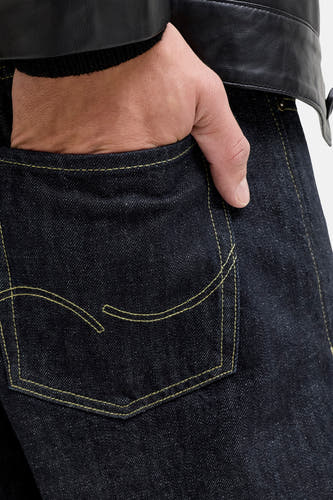 Rechte donkerblauwe denim jeans van JACK & JONES JEANS INTELLIGENCE, met een hand in de achterzak en een leren jas.
