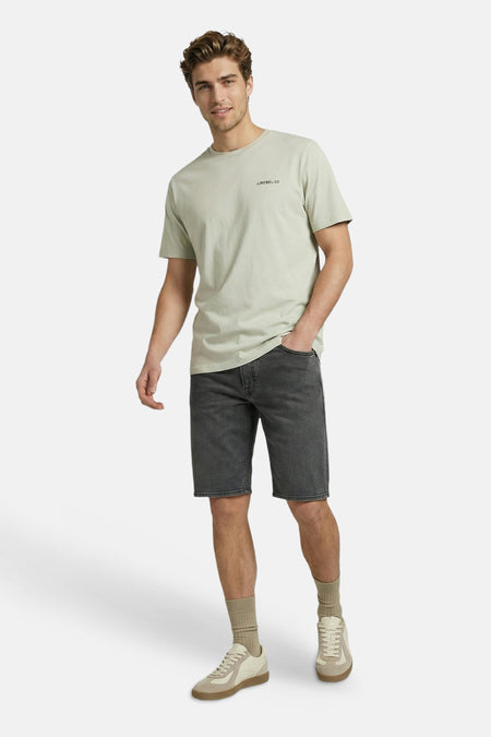 Groen T-shirt met korte mouwen van JJREBEL, met 'JJREBEL/23' tekst op de borst, gedragen door een man met donkergrijze denim shorts.