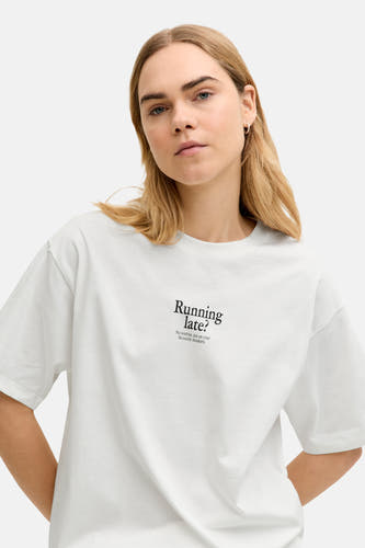 Wit T-shirt met korte mouwen van JJXX, met de tekst "Running late?", gedragen door een blond model.
