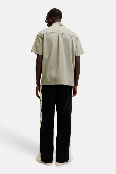 Beige overhemd met korte mouwen van CORE BY JACK & JONES, achterkant, met rugplooien, gedragen met een zwarte broek met zijstreep en witte sneakers.