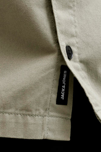 Chemise beige à manches courtes de CORE BY JACK & JONES, avec tissage sergé diagonal, un bouton noir et une étiquette Jack & Jones noire.