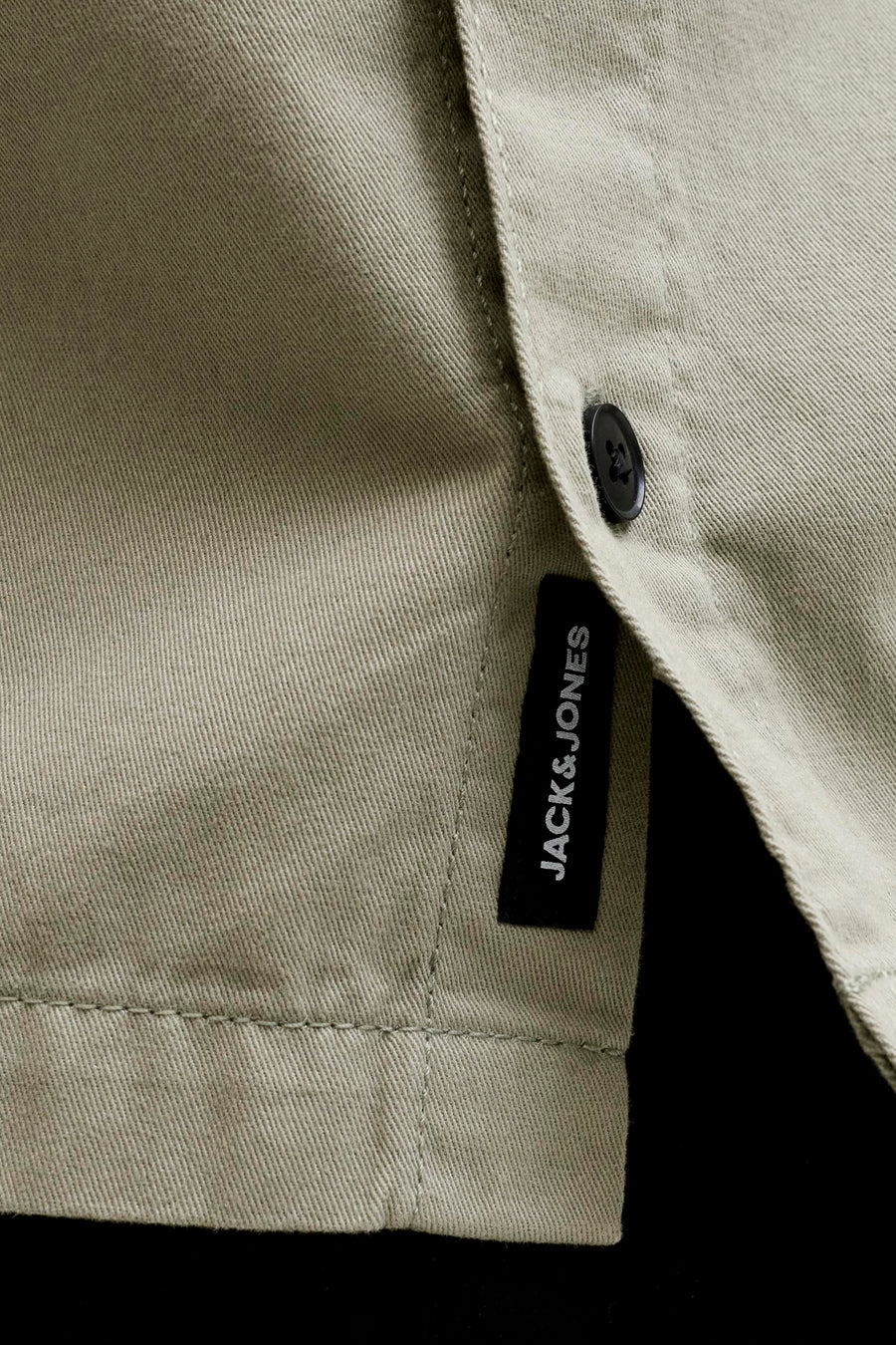 Chemise beige à manches courtes de CORE BY JACK & JONES, avec tissage sergé diagonal, un bouton noir et une étiquette Jack & Jones noire.