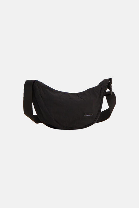 Zwarte schoudertas van ACCESSORIES BY JACK & JONES met een gebogen ontwerp, verstelbare riem en een merklabel.