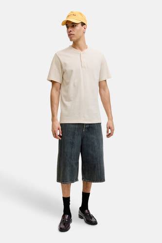 Beige korte mouwen T-shirt met knoopsluiting van PREMIUM by JACK & JONES, gedragen met donkere denim shorts en bruine loafers, front view.