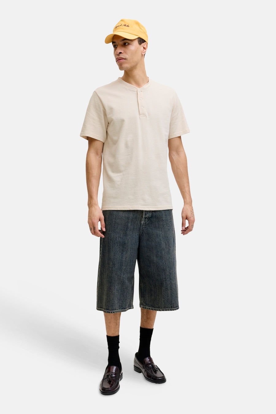Beige korte mouwen T-shirt met knoopsluiting van PREMIUM by JACK & JONES, gedragen met donkere denim shorts en bruine loafers, front view.