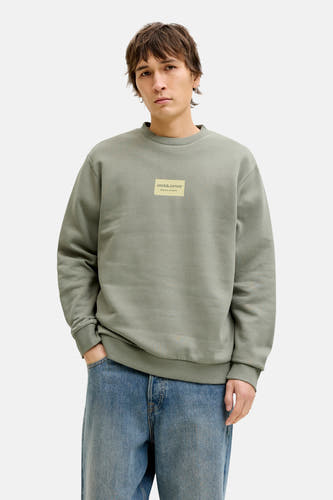 Groene sweater met ronde hals van CORE BY JACK & JONES, met een rechthoekig logo op de borst, gedragen met een blauwe jeans.
