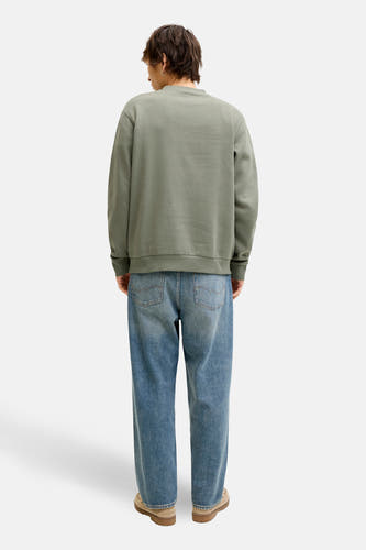 Groene sweater van CORE BY JACK & JONES, met lange mouwen, gedragen met blauwe jeans en suède schoenen.