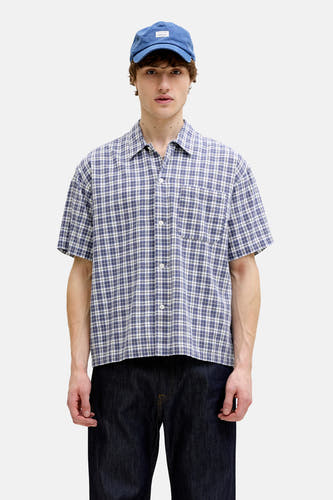 Blauw overhemd met korte mouwen van ORIGINALS BY JACK & JONES met blauw, wit en zwart ruitpatroon, knopen en borstzak, gedragen met blauwe pet en donkere spijkerbroek.