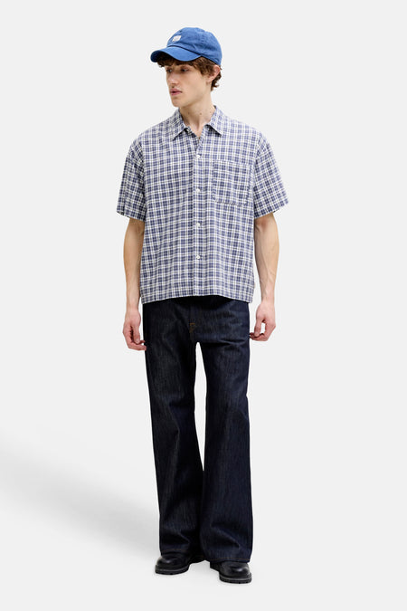 Blauw geruit overhemd met korte mouwen van ORIGINALS BY JACK & JONES, gecombineerd met een donkere spijkerbroek en blauwe pet.