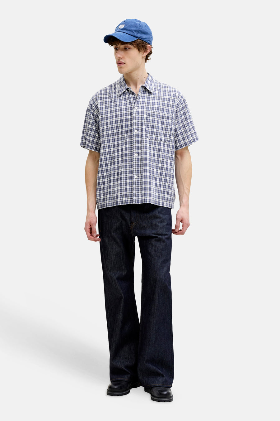 Blauw geruit overhemd met korte mouwen van ORIGINALS BY JACK & JONES, gecombineerd met een donkere spijkerbroek en blauwe pet.