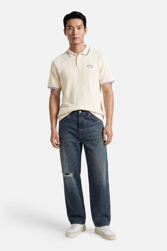 Ecru polo met ribstructuur en blauwe bies, van ORIGINALS BY JACK & JONES, gedragen met gescheurde jeans en witte sneakers, front view