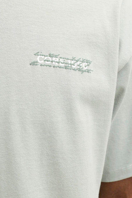 Groen T-shirt met korte mouwen van CORE BY JACK & JONES, close-up van de borst met geborduurd wit en groen opschrift.