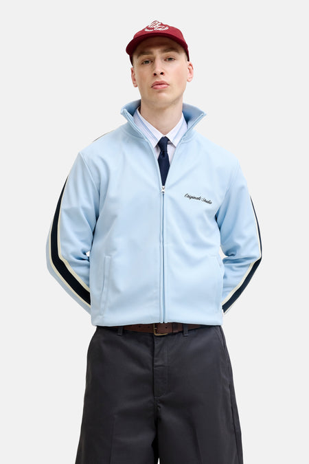 Blauw gilet van Originals by Jack & Jones met ritssluiting, gestreepte mouwen en logo, gedragen met overhemd, stropdas en rode pet.