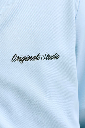 Blauw gilet van ORIGINALS BY JACK & JONES, detailopname met geribbelde textuur, diagonaal patroon en geborduurde zwarte 'Originals Studio' tekst.