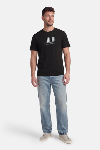 T-shirt noir à manches courtes de CORE by JACK & JONES, avec imprimé graphique et porté avec un jean et des baskets.