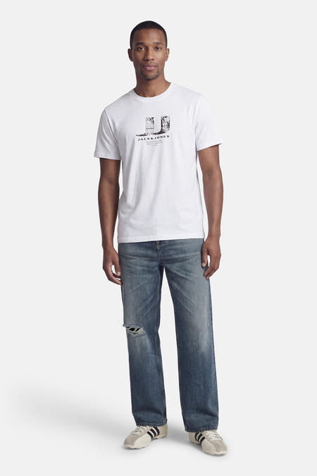 Wit T-shirt met korte mouwen van CORE BY JACK & JONES, met print op de borst, gedragen met blauwe jeans en sneakers.