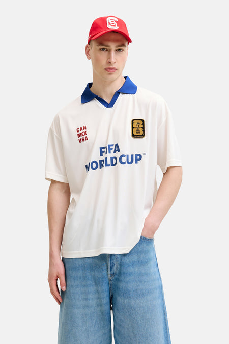 Witte polo van ORIGINALS BY JACK & JONES met blauwe kraag, rode 'CAN MEX USA' en blauwe FIFA World Cup opdrukken, plus gouden WK-patch.