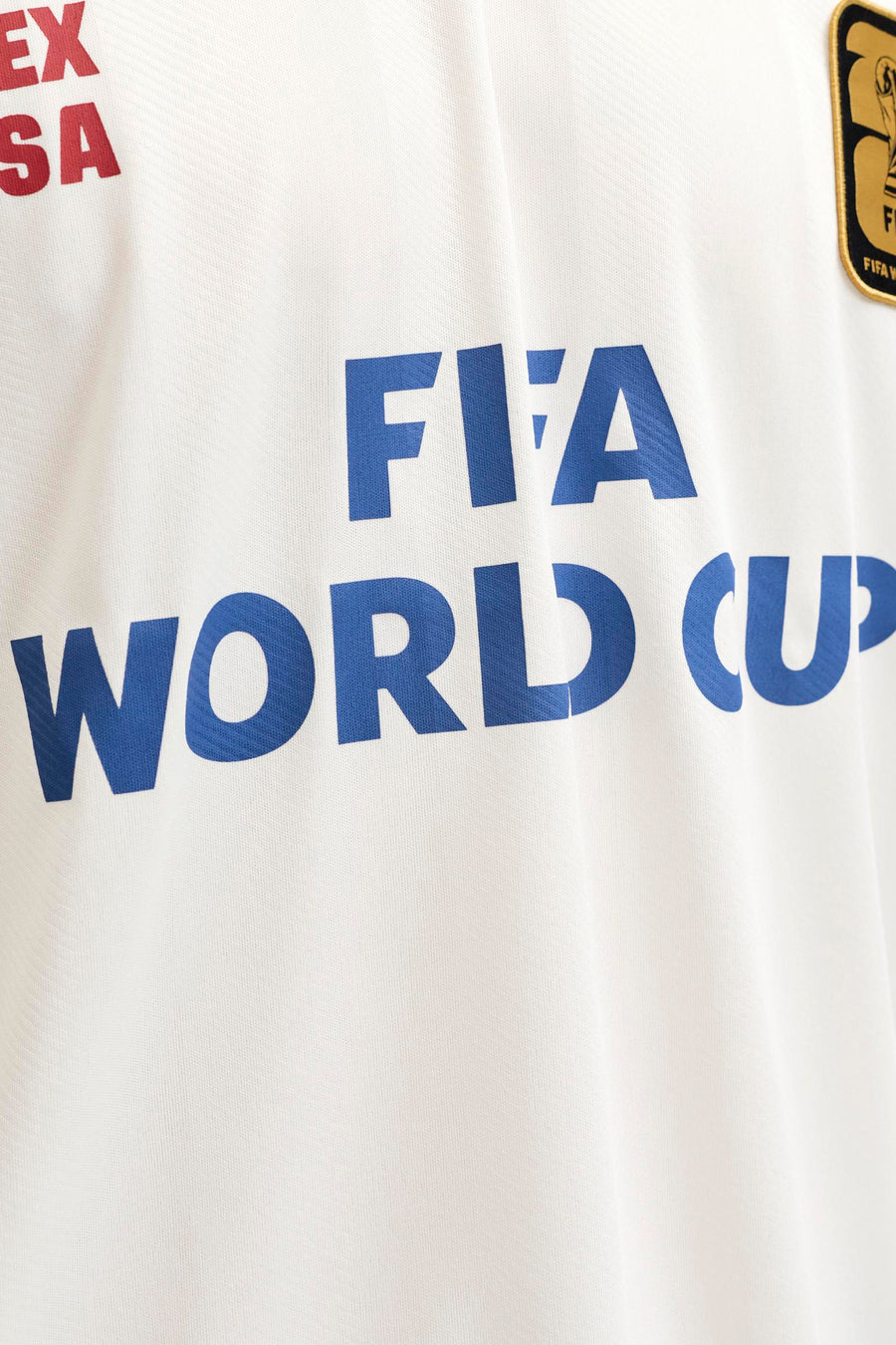 Witte polo van ORIGINALS BY JACK & JONES met blauwe 'FIFA WORLD CUP' opdruk, rood 'EX SA' opschrift en een goudkleurig FIFA World Cup-embleem.