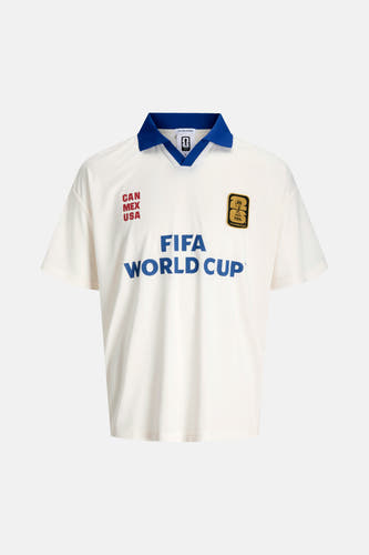 Witte polo van ORIGINALS BY JACK & JONES met blauwe kraag, rode 'CAN MEX USA' tekst, gouden FIFA 26 patch en blauwe 'FIFA WORLD CUP' letters.