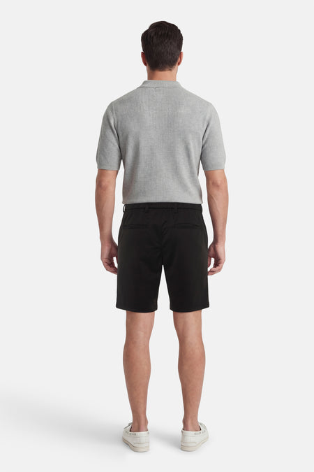 Zwarte short van JACK & JONES JEANS INTELLIGENCE, gezien van achteren, gecombineerd met een grijs poloshirt en witte schoenen.