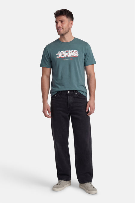 Groen T-shirt met korte mouwen van CORE by JACK & JONES, met een bedrukte tekst, gedragen met zwarte jeans en grijze sneakers.
