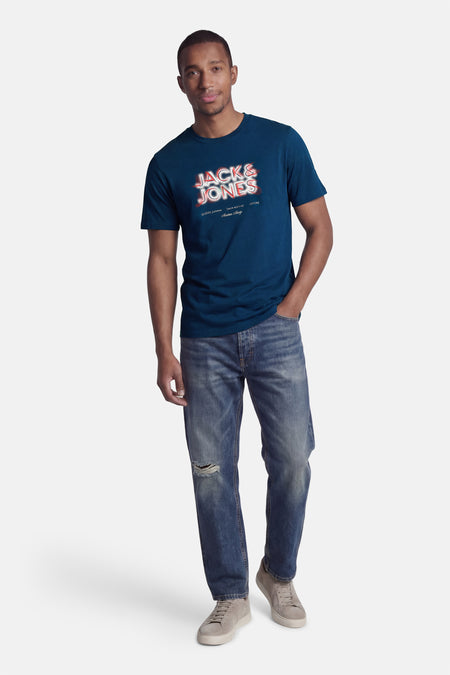 Blauw T-shirt met korte mouwen van CORE BY JACK & JONES, met een grafische print, gecombineerd met jeans met een gat en grijze sneakers.
