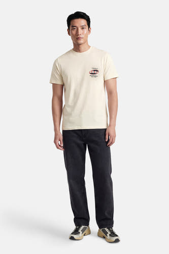 Ecru T-shirt met korte mouwen van ORIGINALS by JACK & JONES, met een logo op de borst, gecombineerd met een donkere jeans en sneakers.