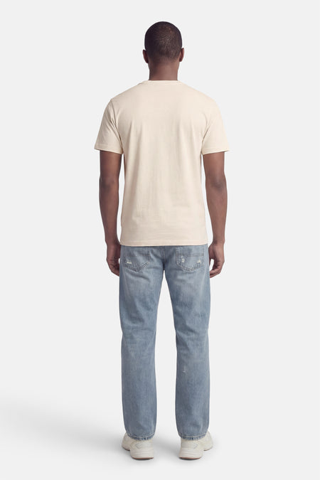 Ecru T-shirt met korte mouwen van ORIGINALS BY JACK & JONES, achterkant, gecombineerd met blauwe spijkerbroek en witte sportschoenen.