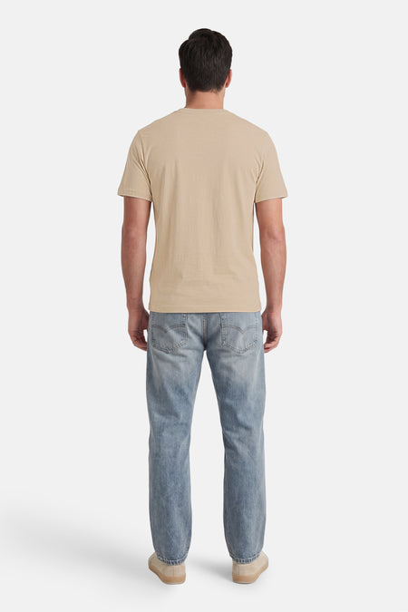 T-shirt beige à manches courtes de CORE BY JACK & JONES, vu de dos, porté par un homme avec un jean et des baskets.