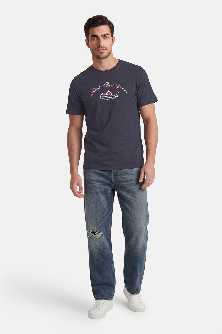 T-shirt gris de ORIGINALS BY JACK & JONES avec logo 'Jack And Jones Originals' sur la poitrine, porté avec un jean déchiré et des baskets blanches.