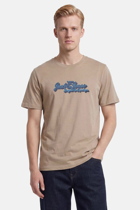 Beige T-shirt met korte mouwen van Jack & Jones, met een blauwe logoprint op de borst, gedragen door een man.