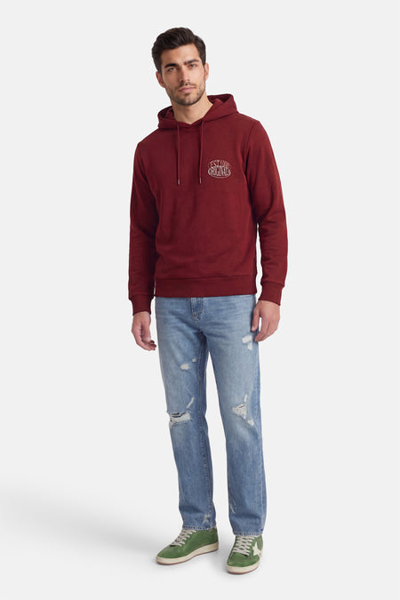 Rode sweater met capuchon van ORIGINALS BY JACK & JONES, met een logo op de borst, gecombineerd met een jeans en groene sneakers.