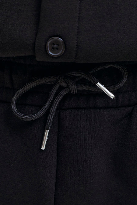 Zwarte heren korte joggingbroek van JACK & JONES JEANS INTELLIGENCE met trekkoord en zilveren tip, close-up detail van taille en knoop.