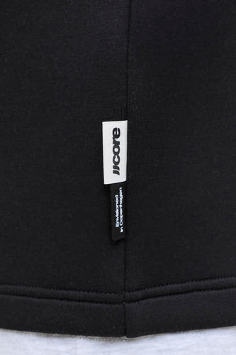 Zwarte ronde hals sweater van CORE BY JACK & JONES, met wit label en fijne ribstructuur, close-up detail van zoom en naden
