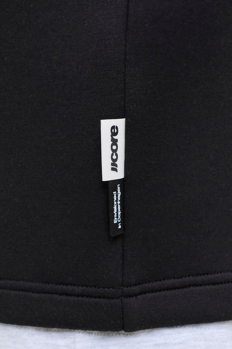 Zwarte ronde hals sweater van CORE BY JACK & JONES, met wit label en fijne ribstructuur, close-up detail van zoom en naden