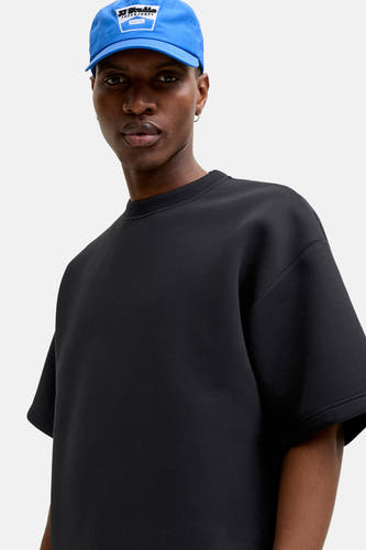 Zwart ronde hals sweater van CORE BY JACK & JONES, oversize fit, gladde stof, model draagt blauwe pet, vooraanzicht