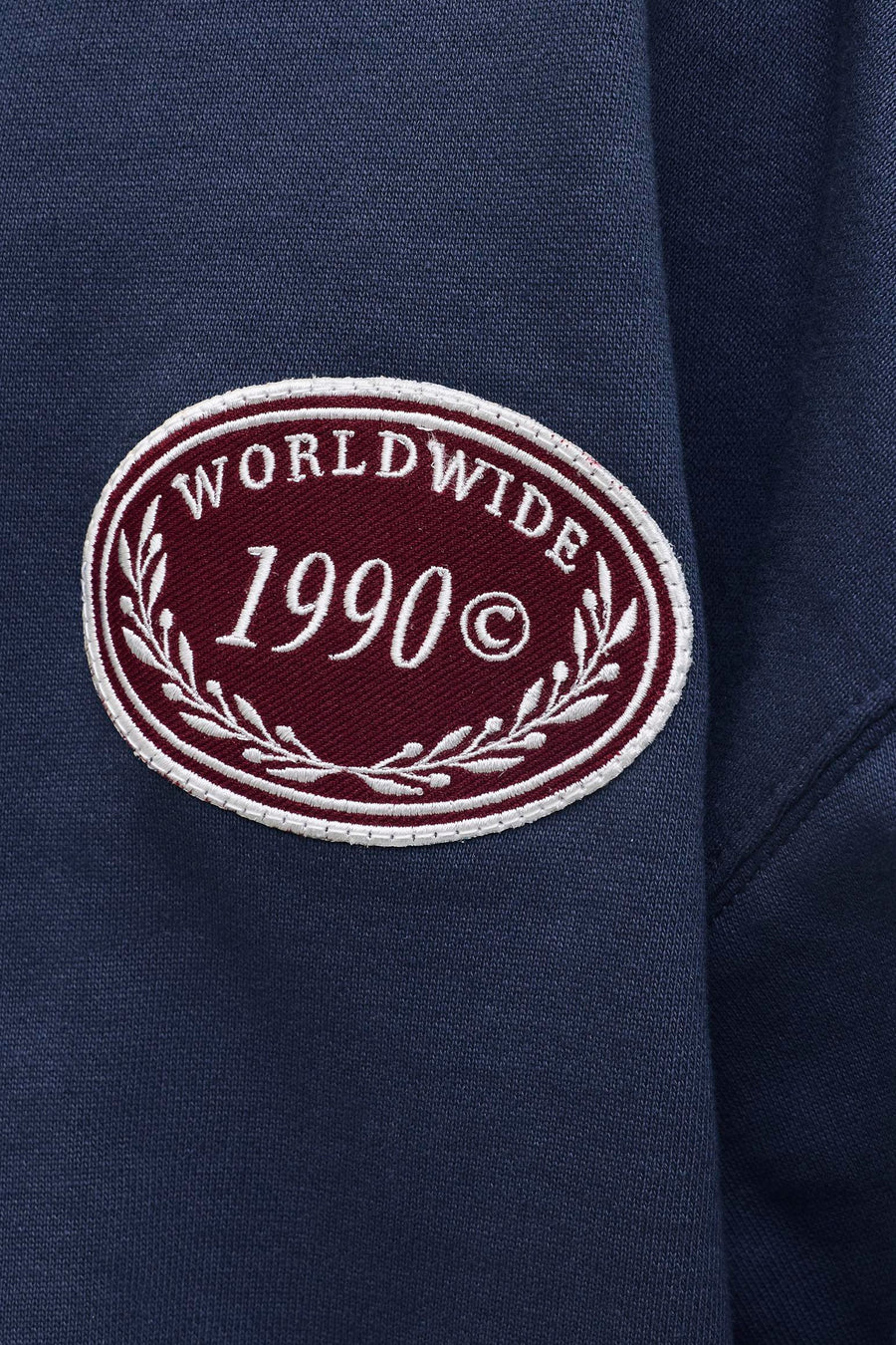 Navyblauwe sweater met ronde hals van ORIGINALS BY JACK & JONES, met een geborduurde bordeauxrode patch met 'WORLDWIDE 1990©'.